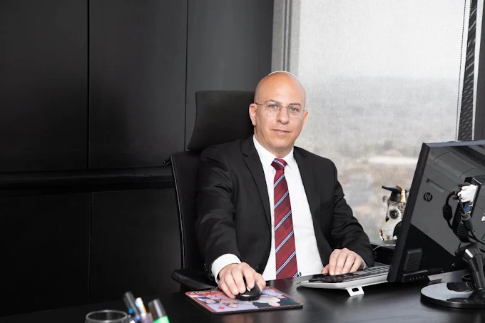 עו"ד מיקי שיפמן יושב ליד שולחן ומחשב